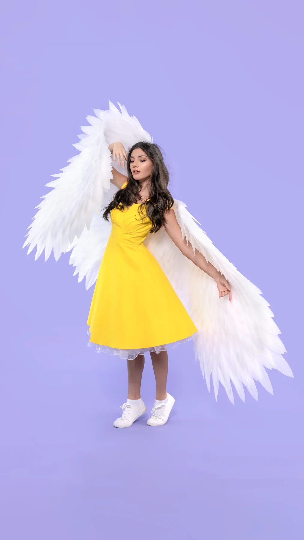Model wearing white angel wings and a yellow dress