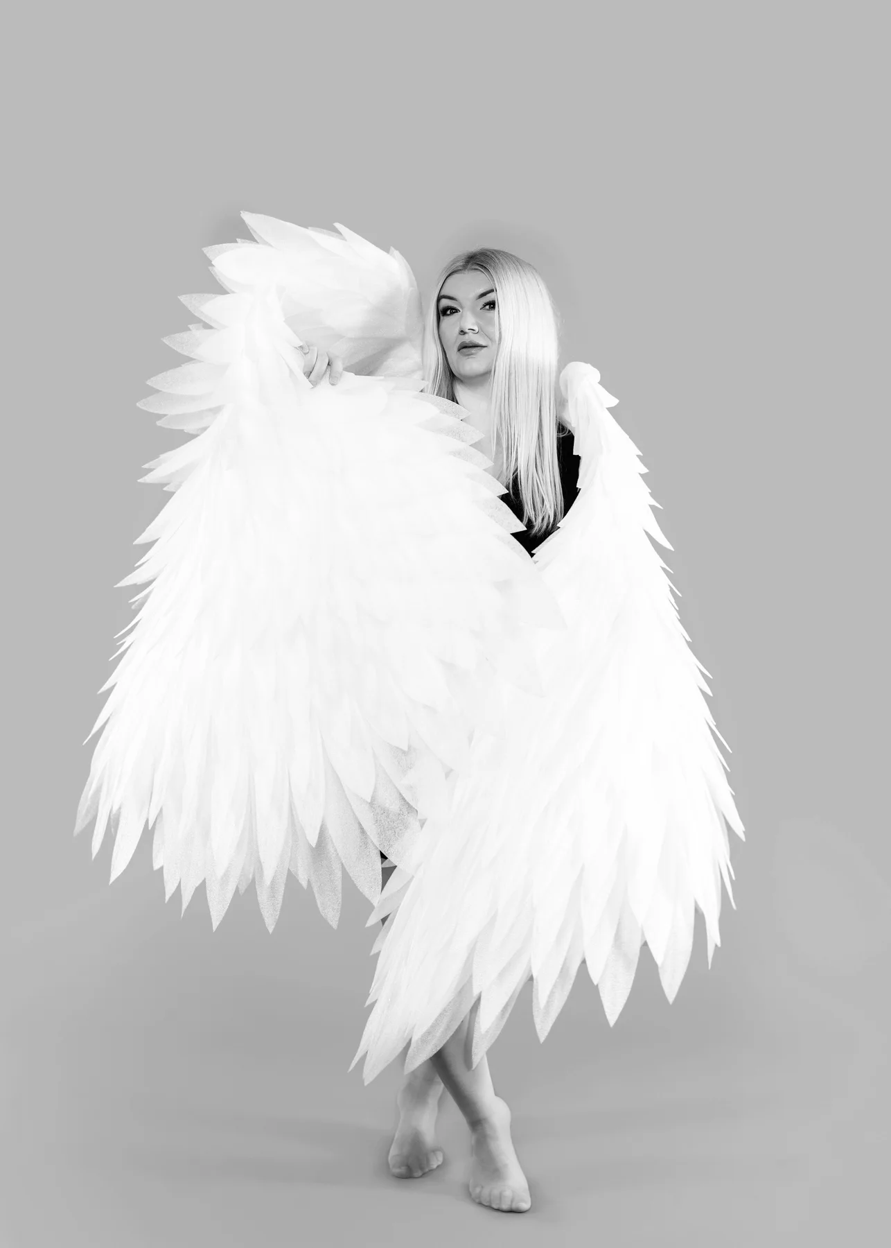 Monochrome studio portrait with white feather wings